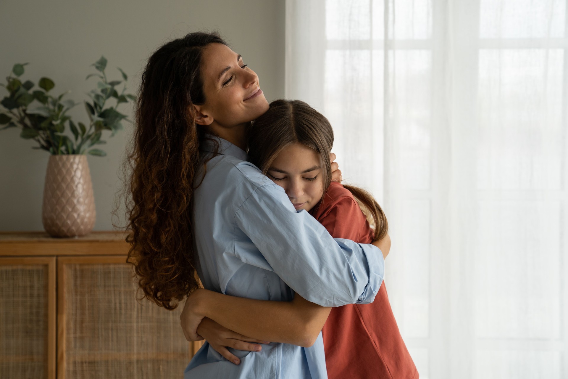 Young loving mother hugging teenage daughter at home, mom cuddling supporting upset teen girl
